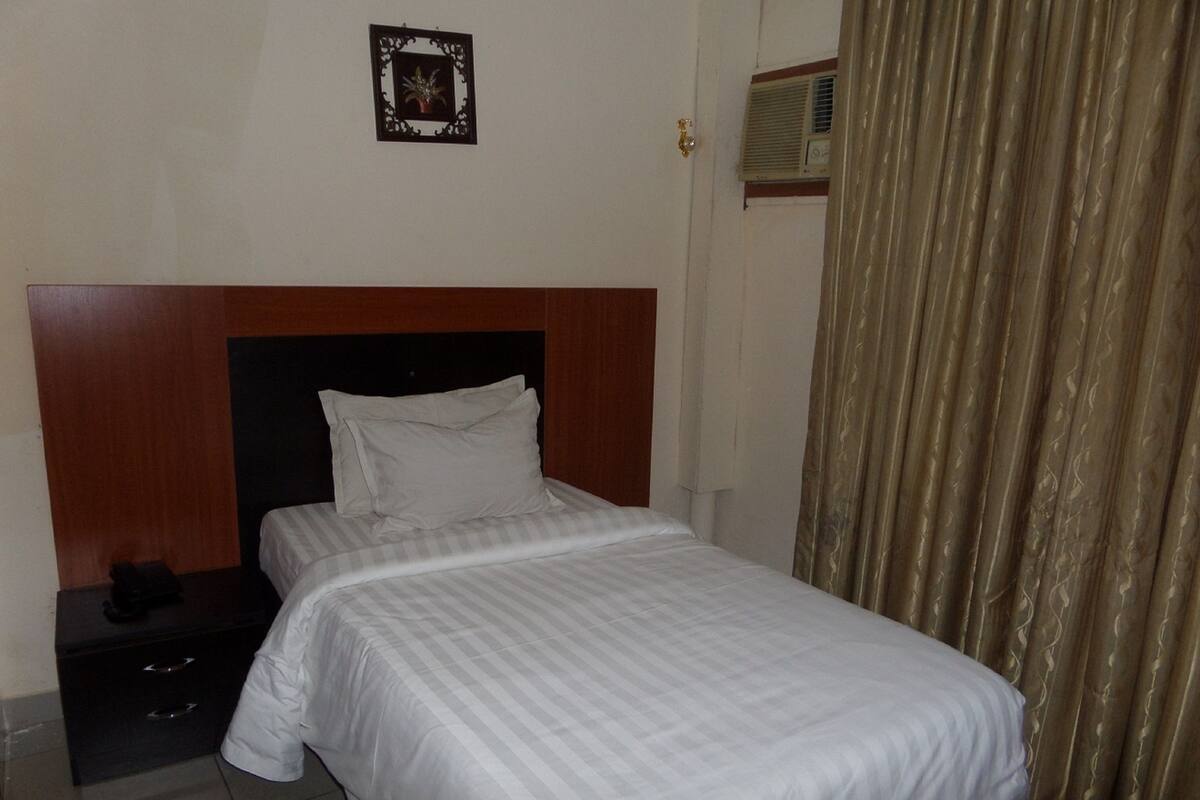 Una cama bien hecha con ropa blanca en una habitación de hotel.
