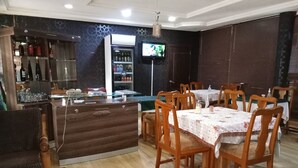 A restaurant with a bar area, wooden chairs, and tables. - Dreamland Suites (Abuja)