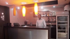 Zona de recepción con mostrador, refrigerador y estantes con botellas.