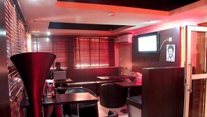 Un restaurante con una decoración moderna, que presenta muebles de madera oscura, una pared de acento roja y un televisor montado en la pared.