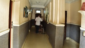 A hallway with a sign for a drinking bar, a television screen, and a person standing near a counter. - Wazobia Plaza Hotel (Lagos)