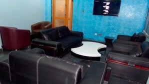 A room with a blue wall, a wooden door, a black sofa, and a small table. - Blue Seasons Hotel & Suites (Lagos)