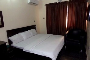 A hotel room with a single bed, a chair, and a TV. - Blue Seasons Hotel & Suites (Lagos)