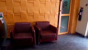 A room with two cushioned chairs, a tiled floor, and a wall with a geometric pattern. - Blue Seasons Hotel & Suites (Lagos)