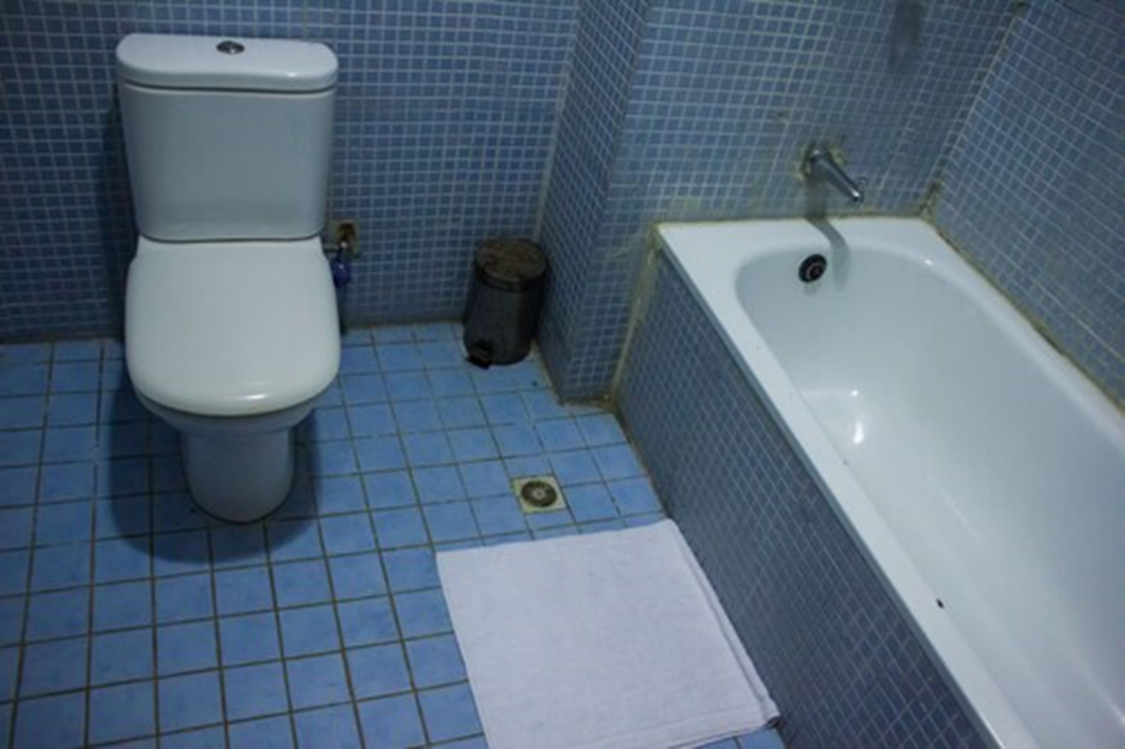 A bathroom with a toilet, a bathtub, and a small trash can.