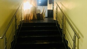 Una escalera conduce a una habitación con una araña, una mesa y una silla cubierta con un mantel.