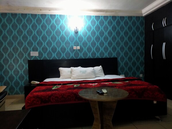 Una habitación de hotel con una cama, una mesita de noche y una pequeña mesa redonda.