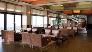 A spacious lobby with wicker furniture, large windows, and a staircase. - Ryokan Kaiyutei (Nishio)