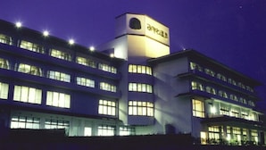 A multi-story building with illuminated windows and a prominent tower with a circular window. - Ryokan Kaiyutei (Nishio)
