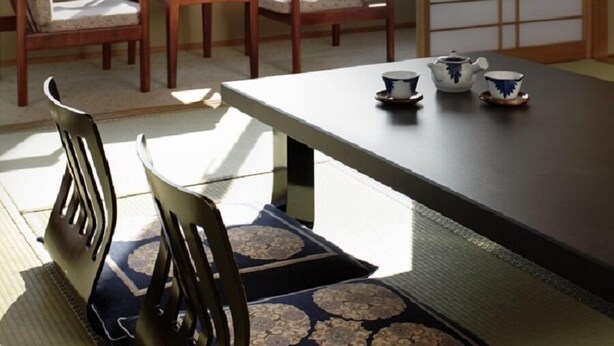 A traditional Japanese room with tatami mats, a low table, and a sliding door. - Ryokan Kaiyutei (Nishio)