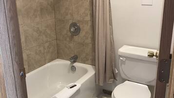 Bañera con ducha, toallas, jabón, shampoo