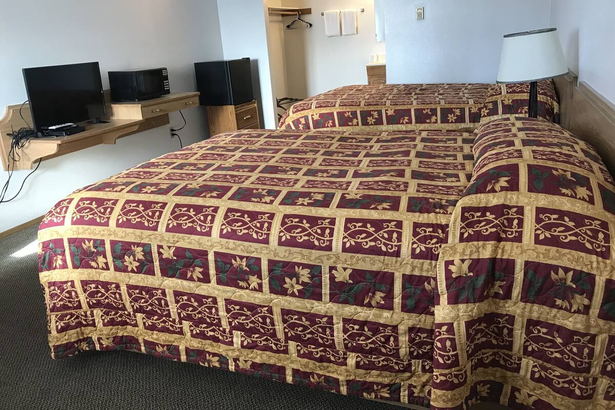 A hotel room with a large bed, a TV on a wooden stand, and a small desk.