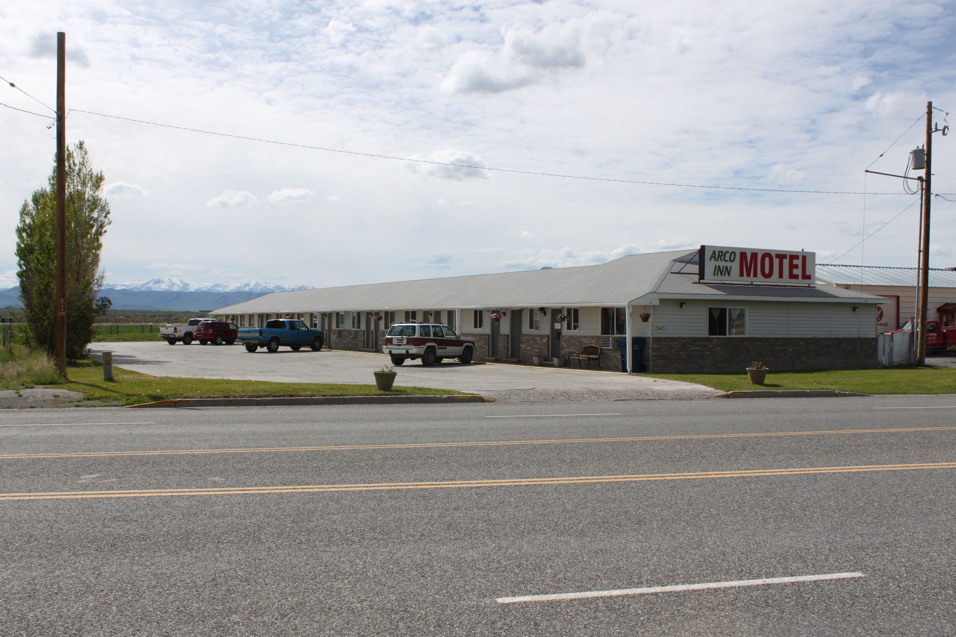 A motel with a signboard, a parking lot, and a mountainous backdrop.