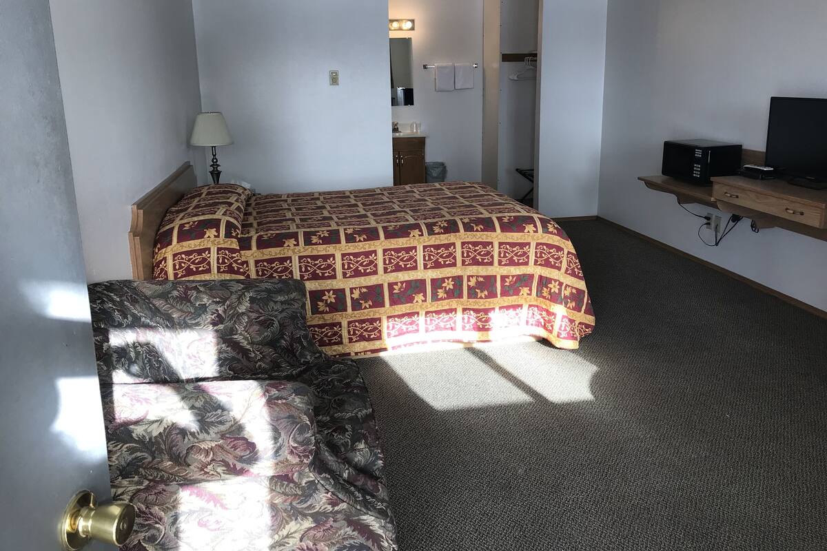 A hotel room with a bed, a sofa, a TV, and a desk with a computer.