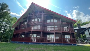 A multi-story wooden building with balconies, large windows, and a red roof. - Chalet Fuyuri (Furano)