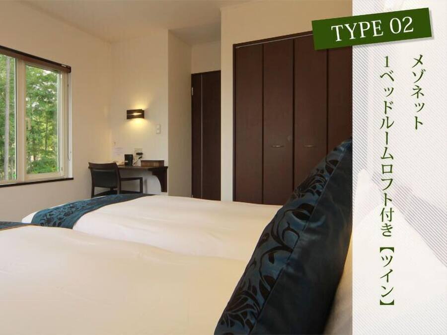 A hotel room with two beds, a desk, and a wardrobe.