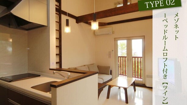 A modern kitchen with a built-in island, wooden beams, and pendant lighting. - Chalet Fuyuri (Furano)