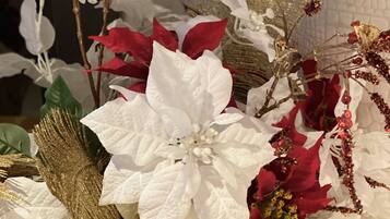 A decorative arrangement with white and red poinsettia plants, gold accents, and a textured wall background.