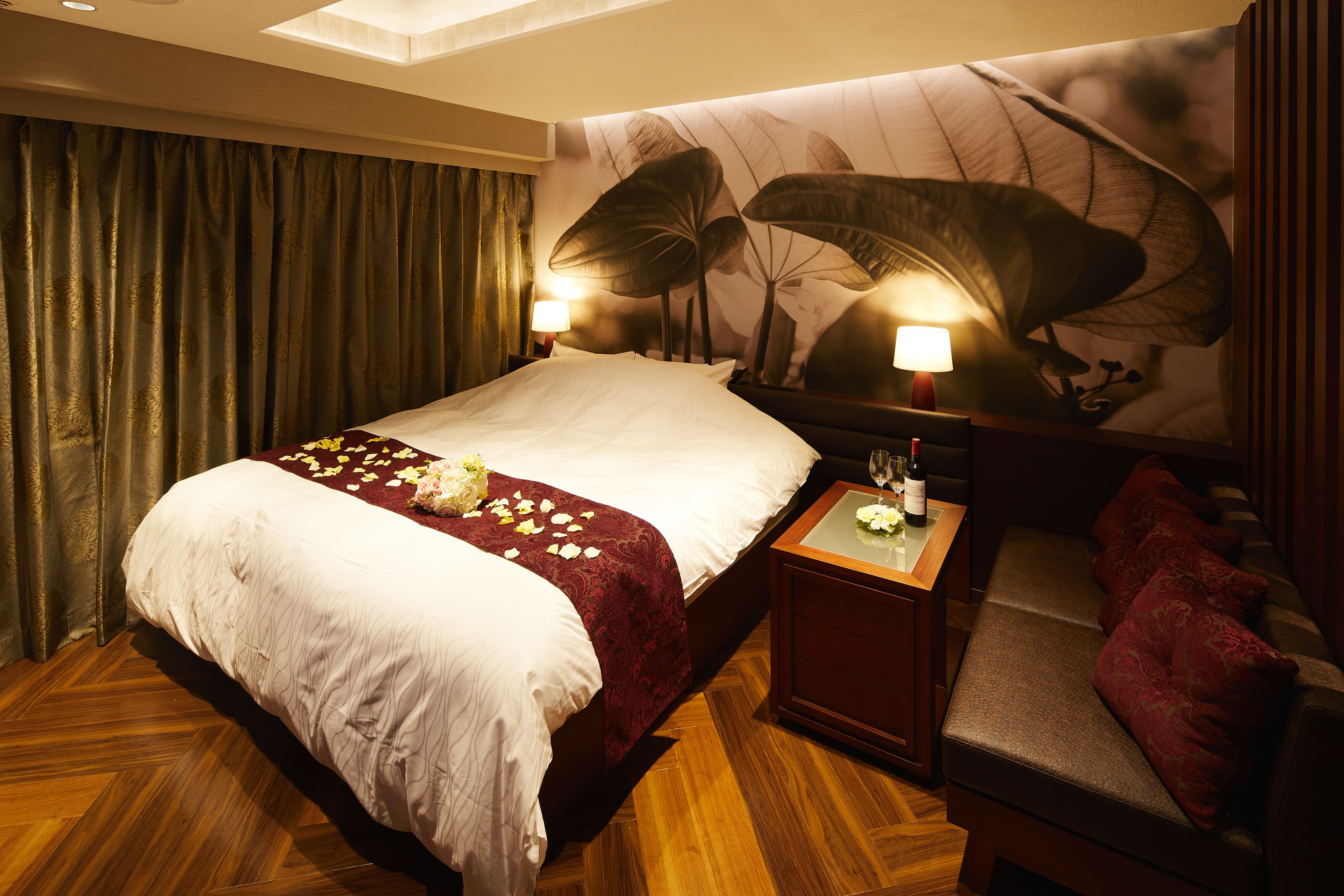 Quarto de hotel com uma cama grande, um espaço de estar pequeno e um mural na parede.