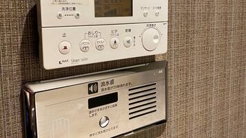 A control panel with a digital display and various buttons for operating a shower system.