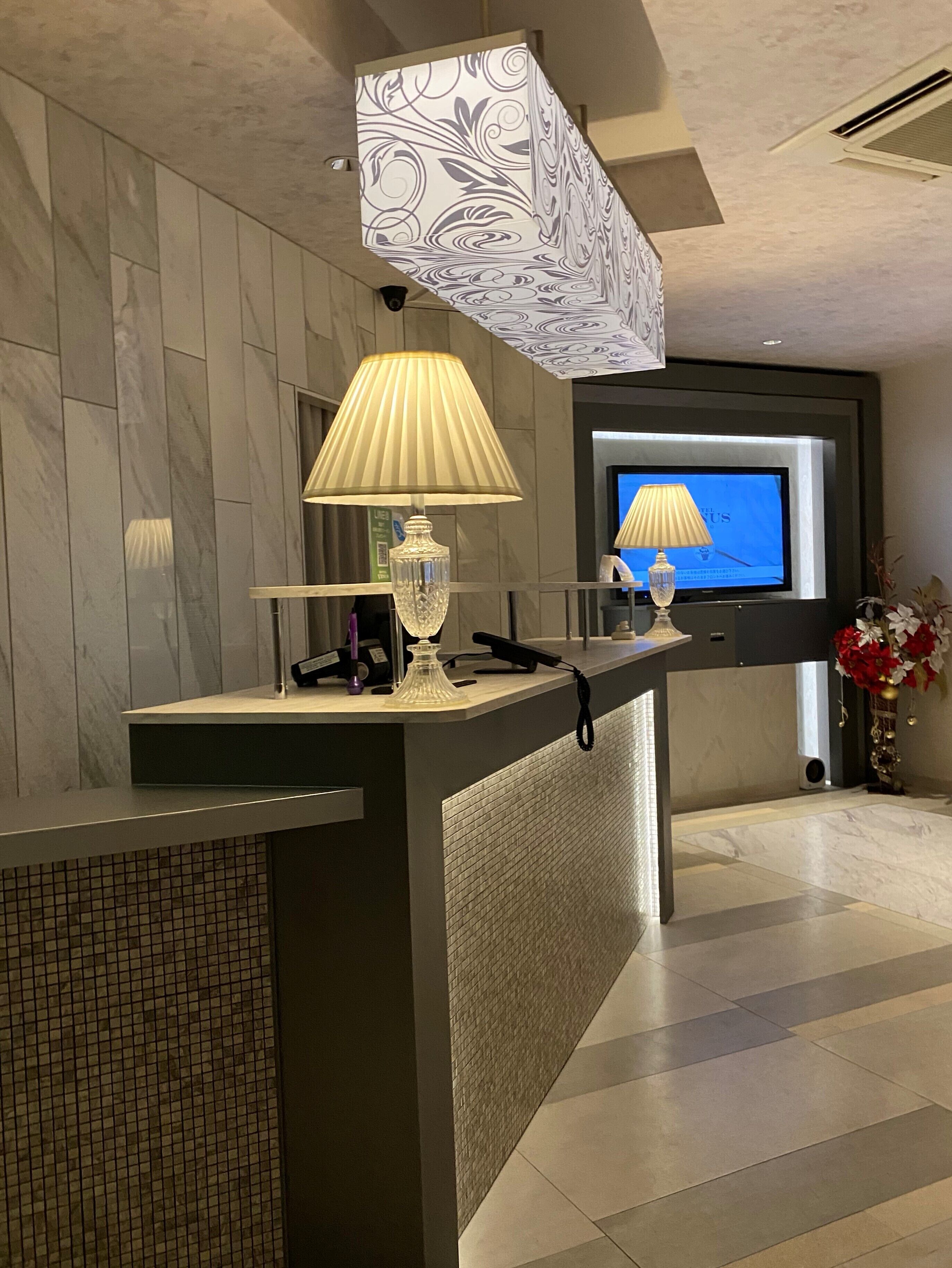 Una moderna recepción con pared de mármol, televisor y una lámpara decorativa.