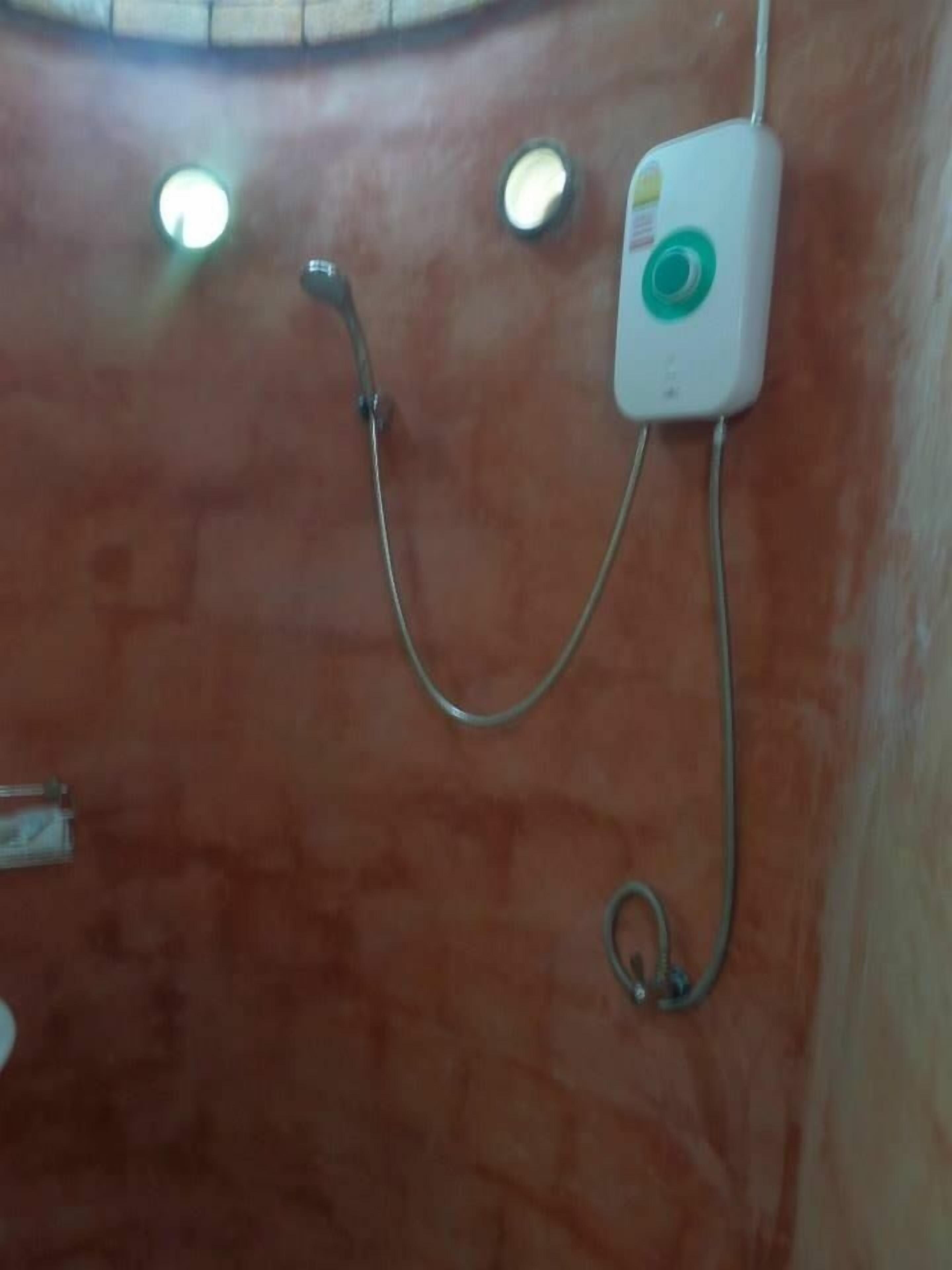 A shower area with a handheld showerhead and a wall-mounted control panel.