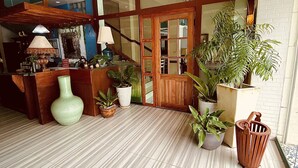 Un hall d’entrée agrémenté d’un lustre, d’un comptoir de réception en bois, de plantes en pot et d’un sol carrelé.