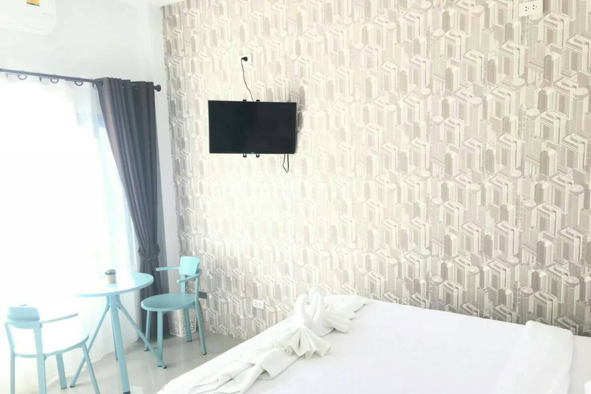 Ein Hotelzimmer mit einem Bett, einem an der Wand montierten Flachbildfernseher und zwei kleinen Tischen mit Stühlen.