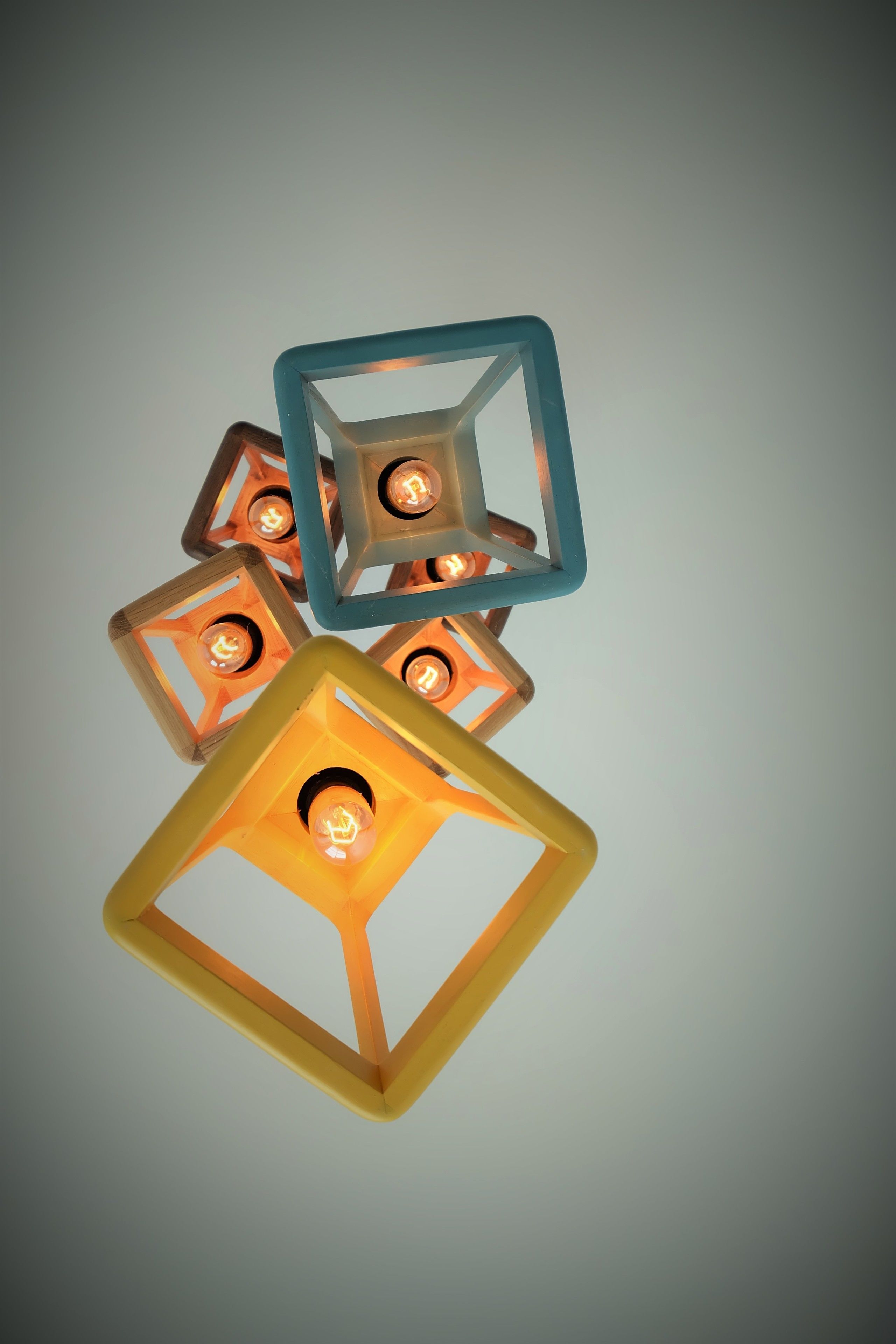 A geometric chandelier with multiple square frames, each containing a light bulb.