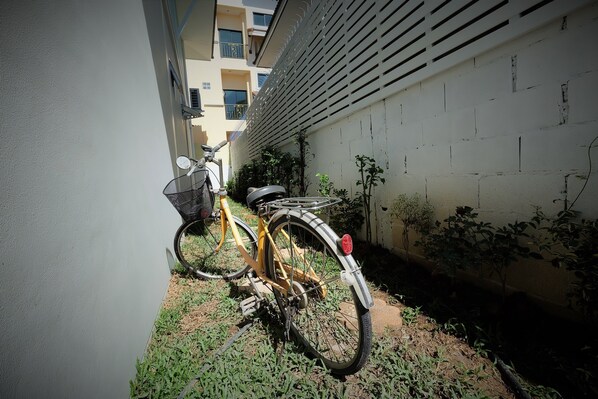 Una bicicleta estacionada contra una pared en un callejón estrecho, con un edificio a un lado y una pared blanca al otro.
