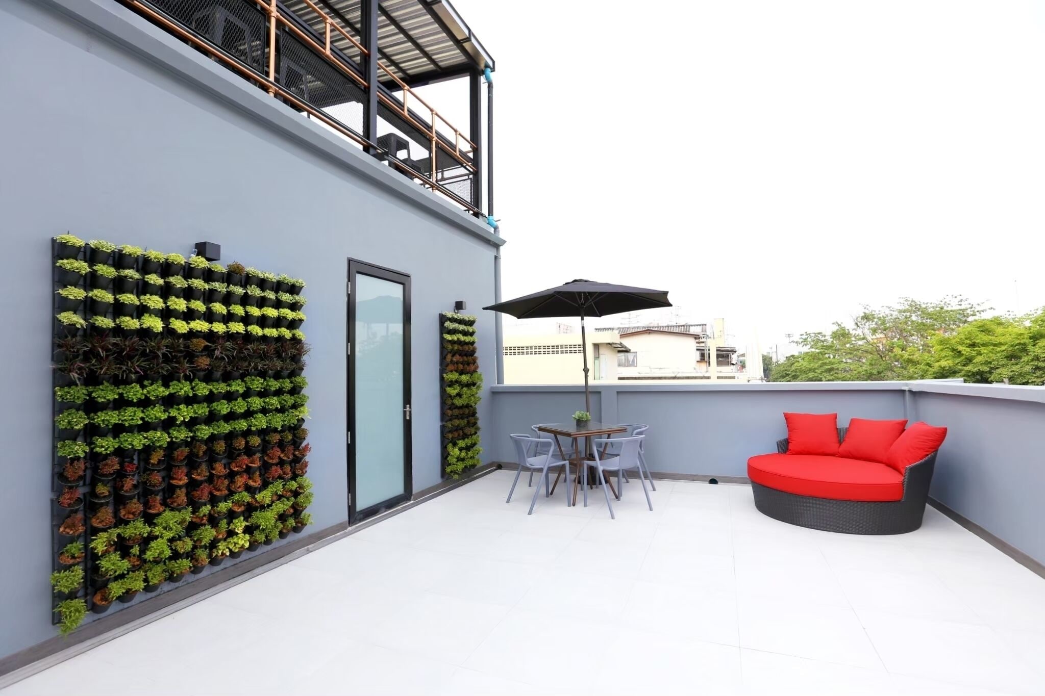 A rooftop terrace with a seating area, a vertical garden, and a glass door.