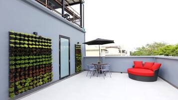 A rooftop terrace with a seating area, a vertical garden, and a glass door.