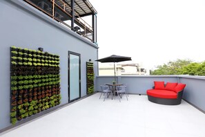 A rooftop terrace with a seating area, a vertical garden, and a glass door. - The Printing House Poshtel - Hostel (Bangkok)