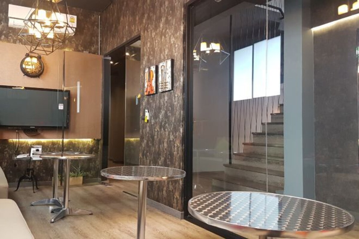A modern interior with two round tables, a television mounted on the wall, and a staircase leading to an upper level.