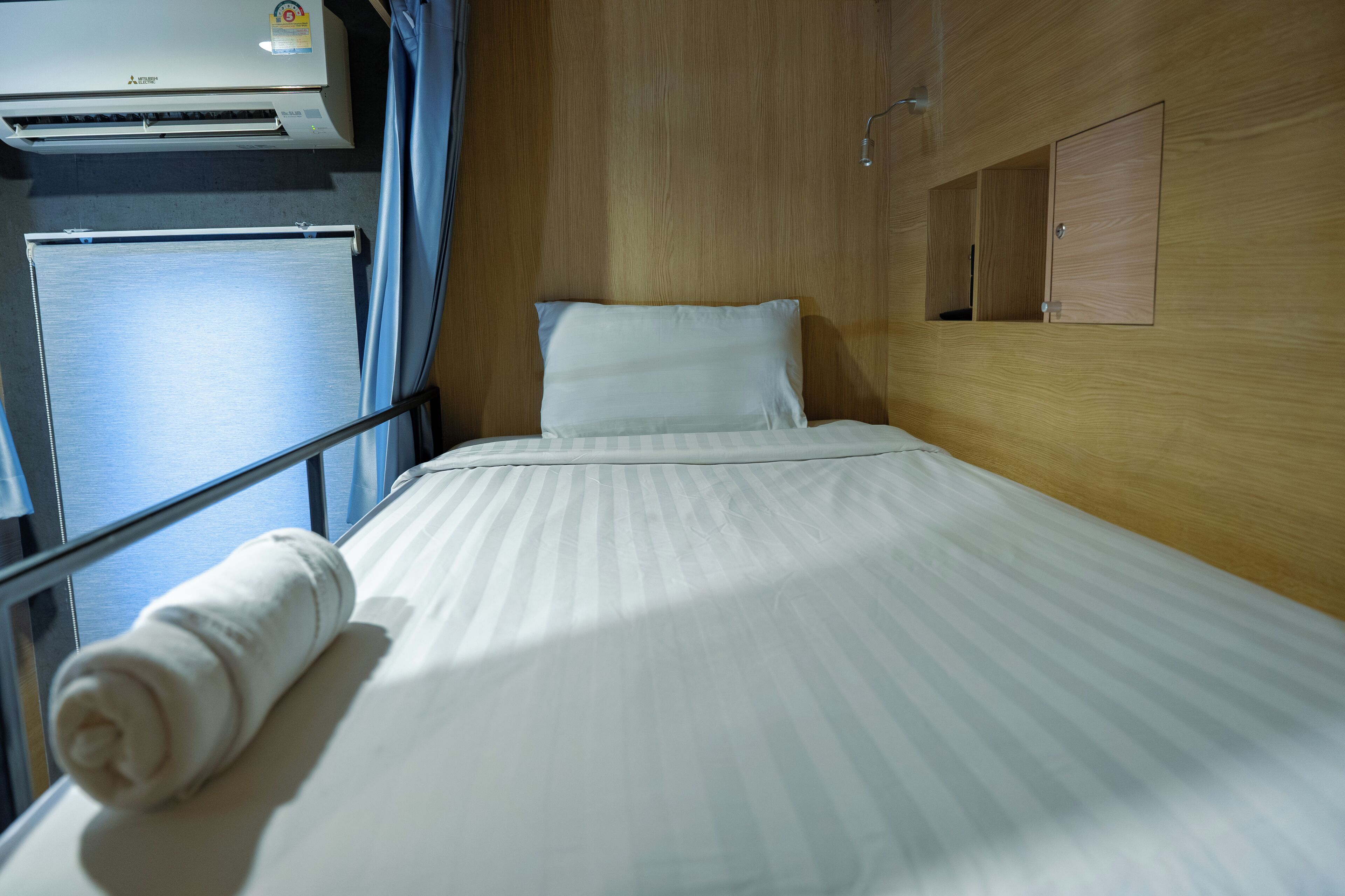 Una camera d'albergo con un letto, una finestra, un condizionatore d'aria e un pannello di parete in legno.