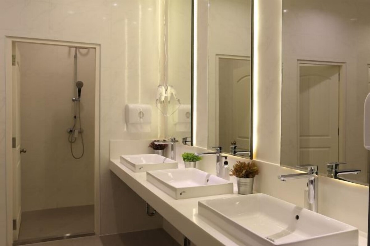 A modern bathroom with two sinks, a large mirror, and a shower.
