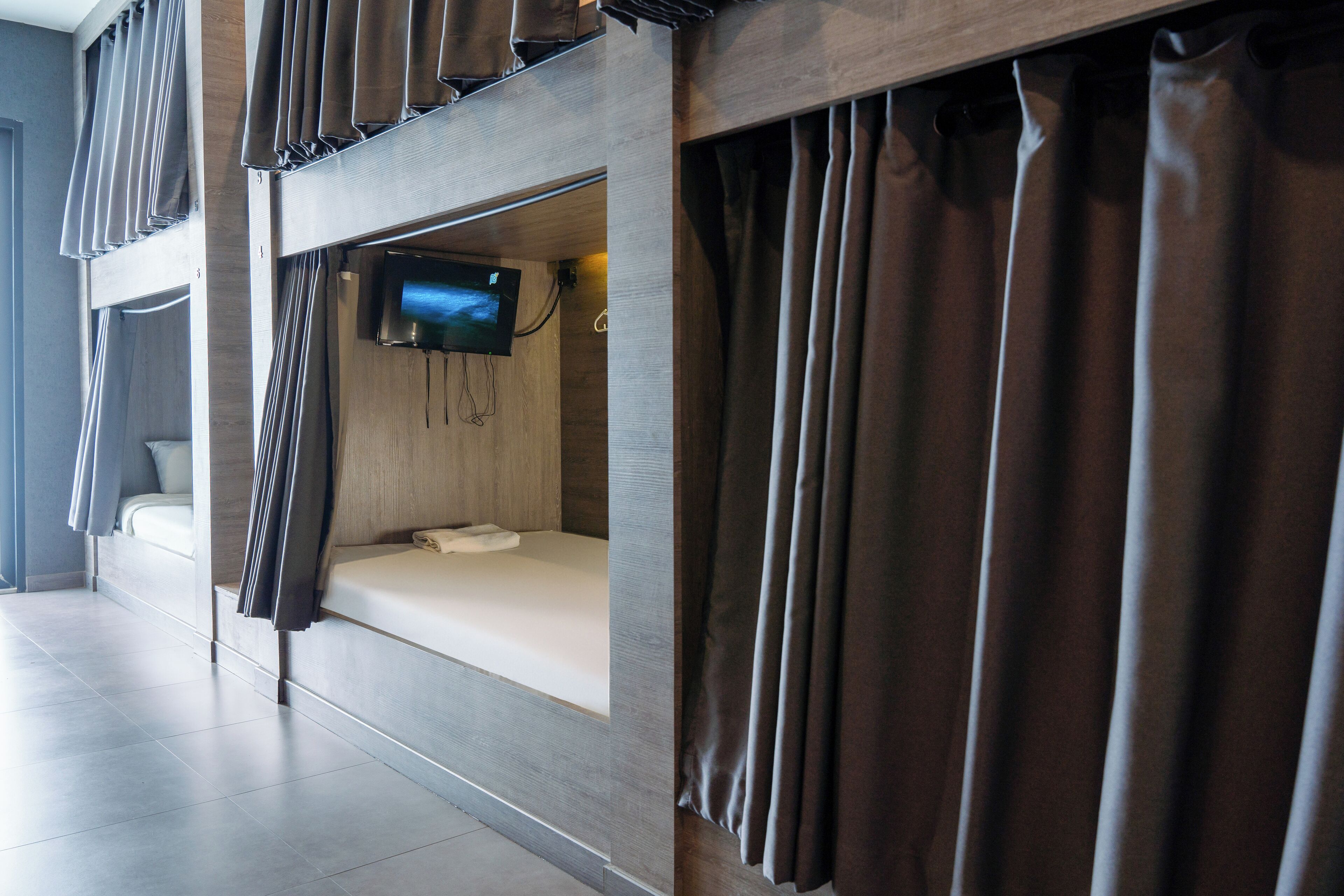 A modern hotel room with a bunk bed, a flat-screen TV, and a small bedside table.