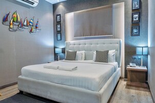 Una habitación de hotel moderna con una cama grande, una mesita de noche con lámpara y un aire acondicionado de pared.