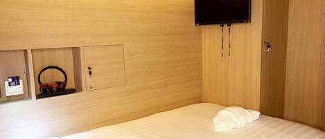 A hotel room with a bed, a television mounted on the wall, and a wardrobe.