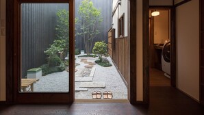 En traditionell japansk inredning med ett golv av tatamimattor, en skjutdörr som leder ut till en trädgård med stenplattor som man kan gå på, och en tvättställ i bakgrunden.