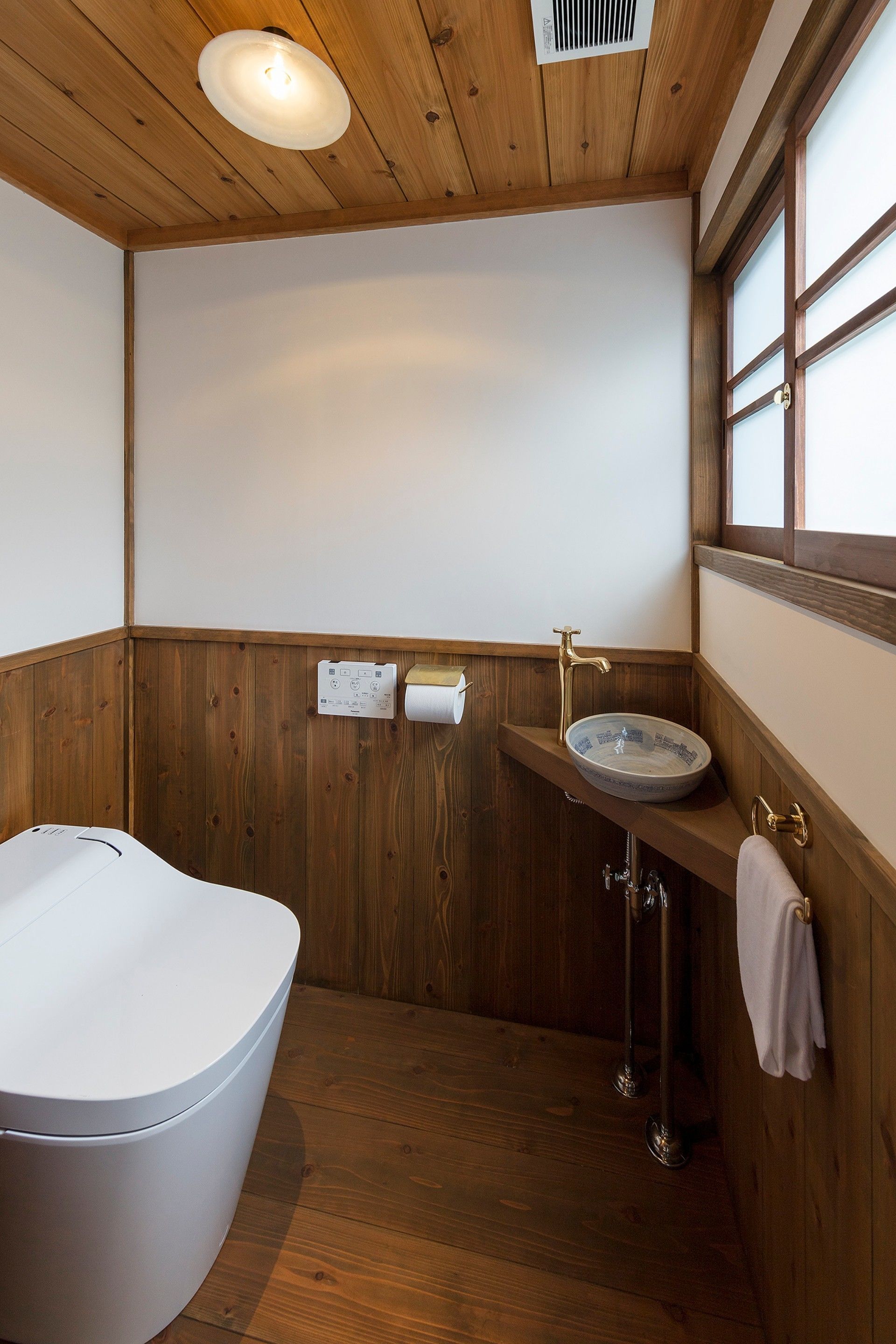 Une salle de bain avec une baignoire sur pieds, un lavabo et une serviette accrochée au mur, ainsi qu’une fenêtre laissant entrer la lumière naturelle.