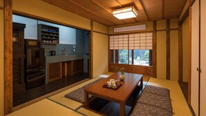 Ett traditionellt japanskt rum med tatamimattor på golvet, ett lågt träbord och en skjutdörr som leder till ett köksområde.
