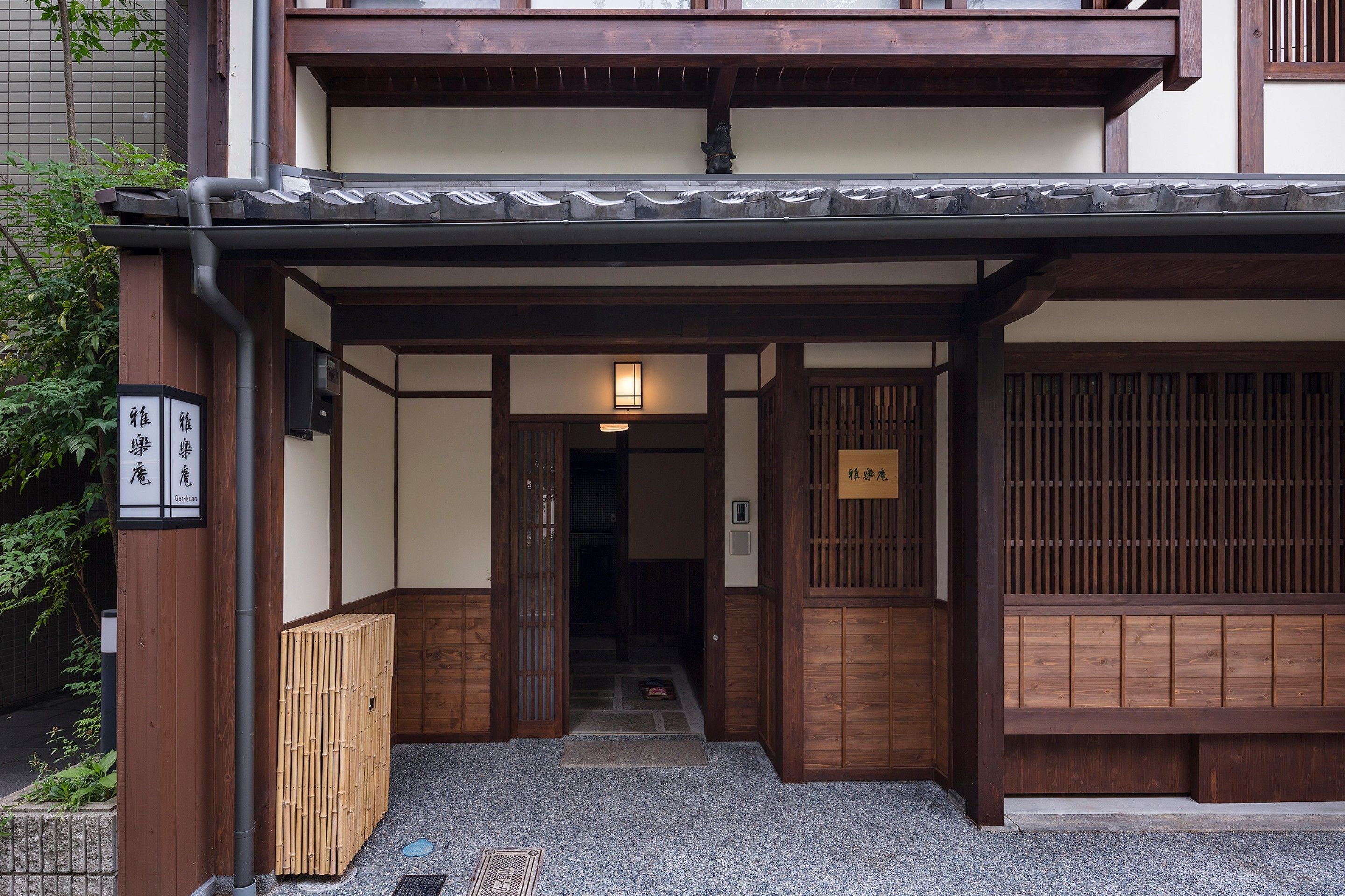 Une entrée de style japonais traditionnel, avec des portes en bois et un toit recouvert de tuiles.