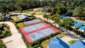 Vista aérea de un resort con varias canchas de tenis, piscina y playa.