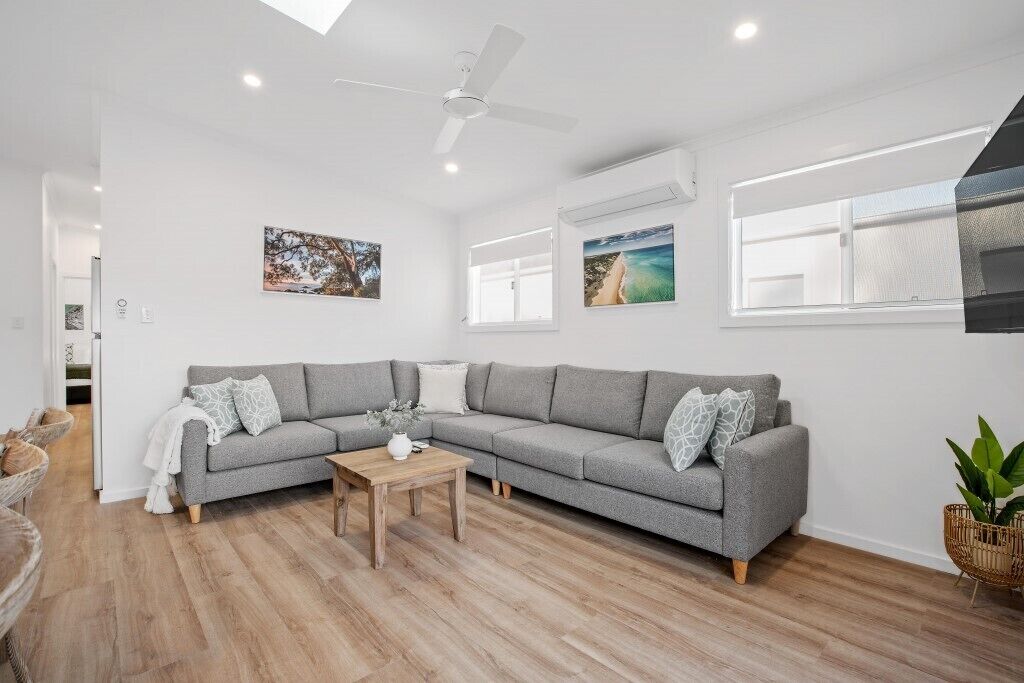 A modern living room with a grey sectional sofa, a wooden coffee table, and a ceiling fan.