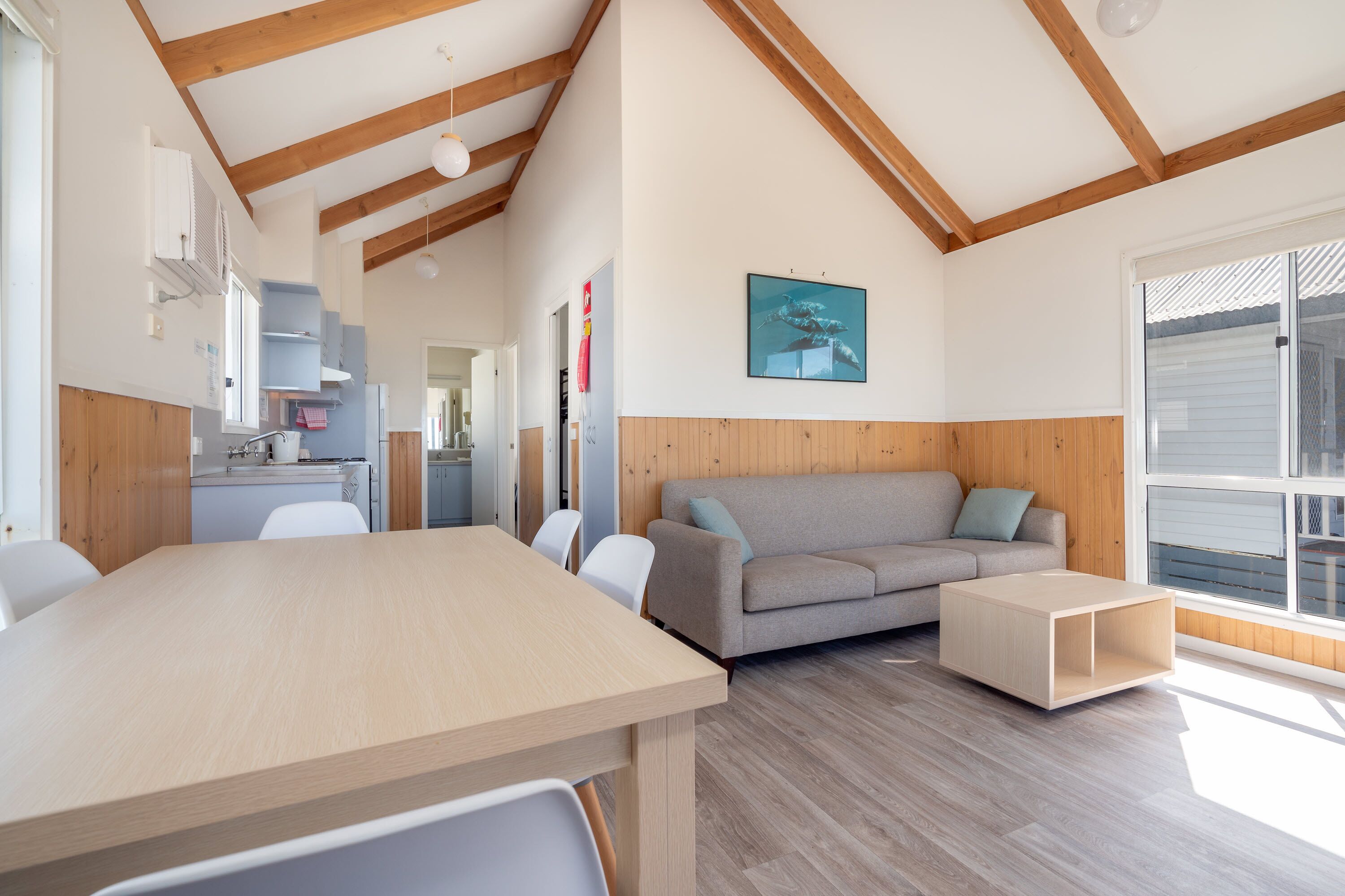 A modern interior with a dining area, sofa, and a kitchen in the background.