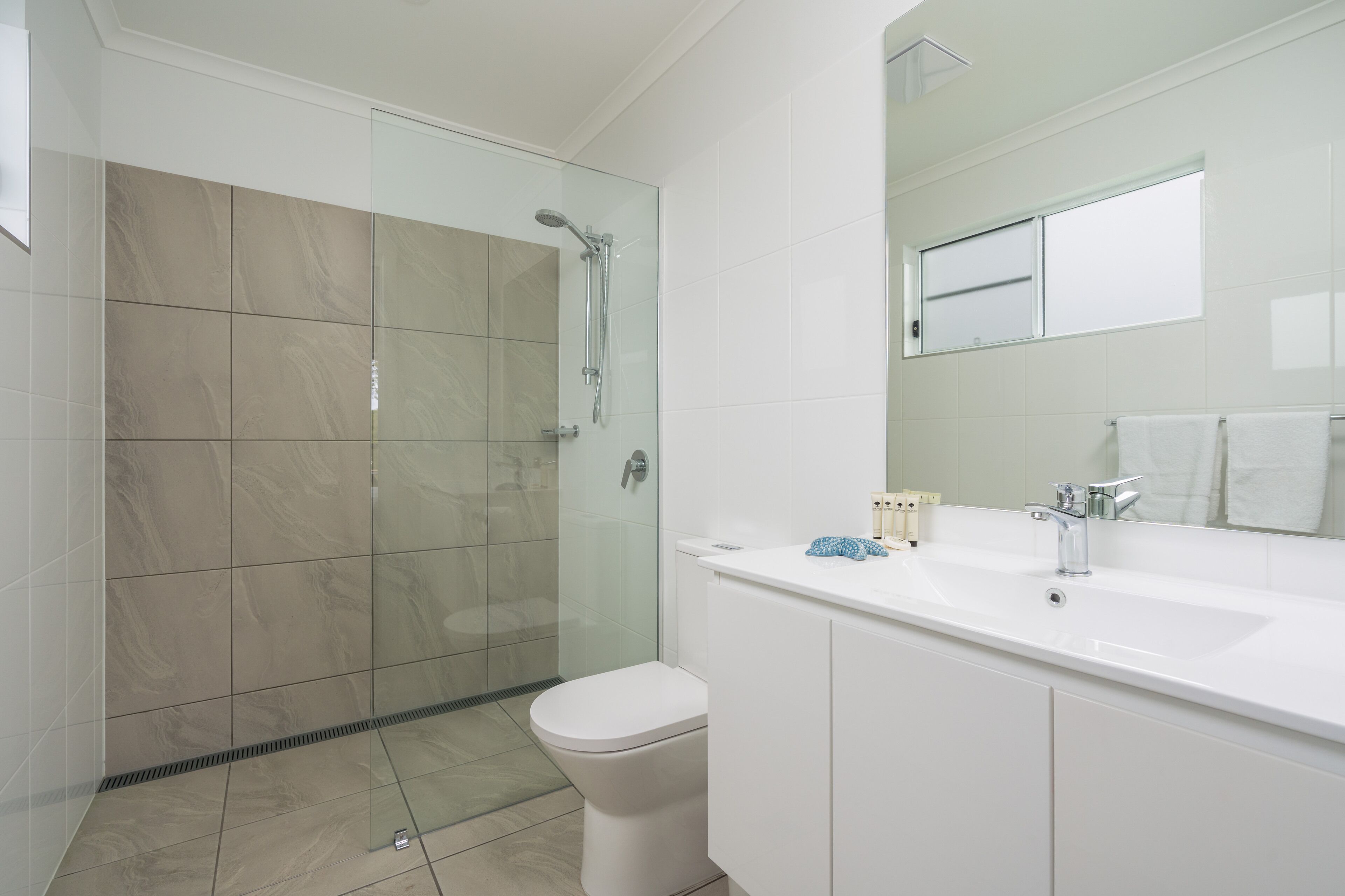 A modern bathroom with a glass-enclosed shower, a white sink, and a toilet.