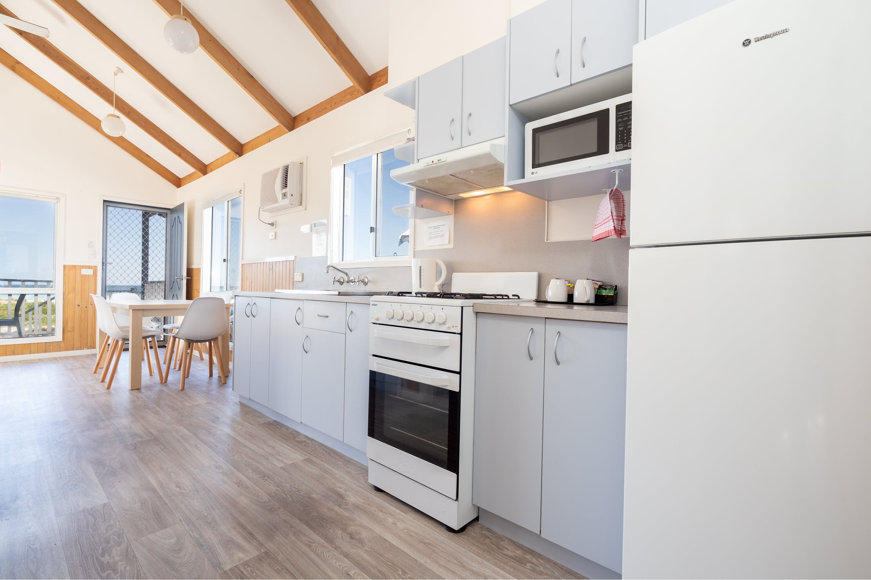 Een moderne keuken met witte kastjes, een inbouwfornuis en een magnetron.
