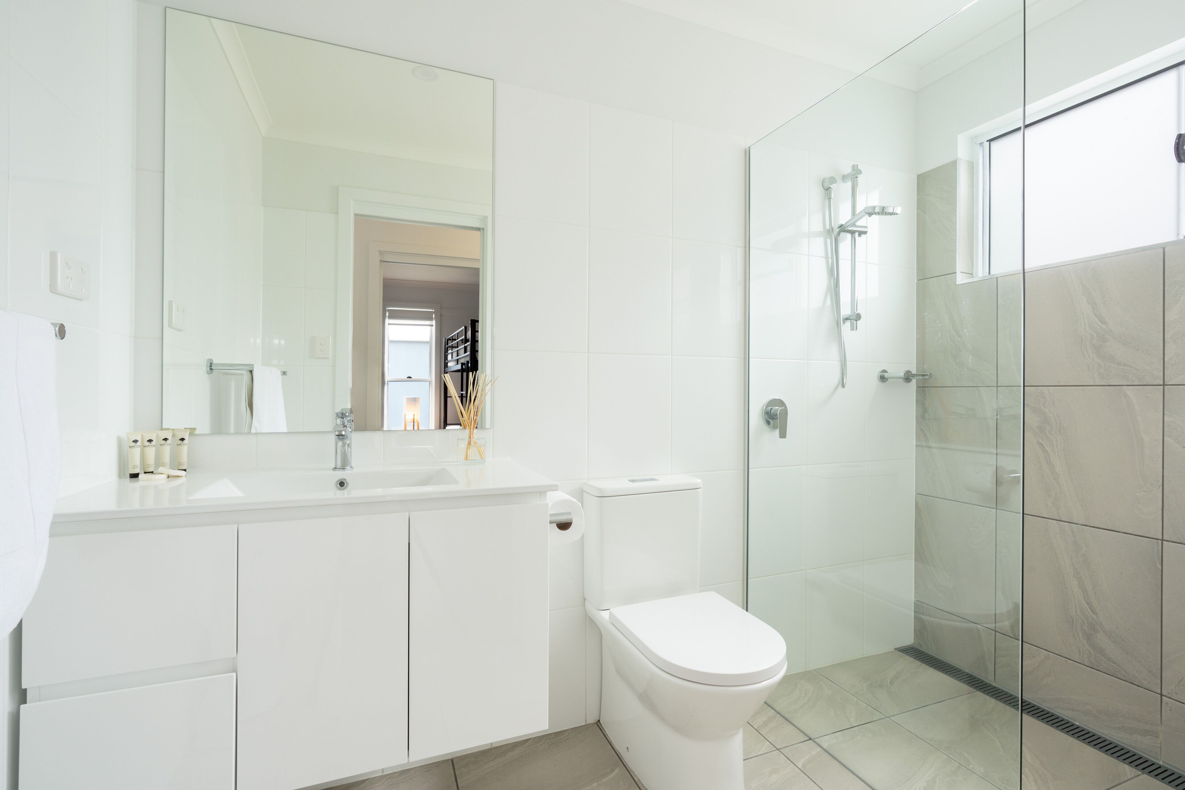 A modern bathroom with a glass shower enclosure, a white toilet, and a vanity with a mirror.