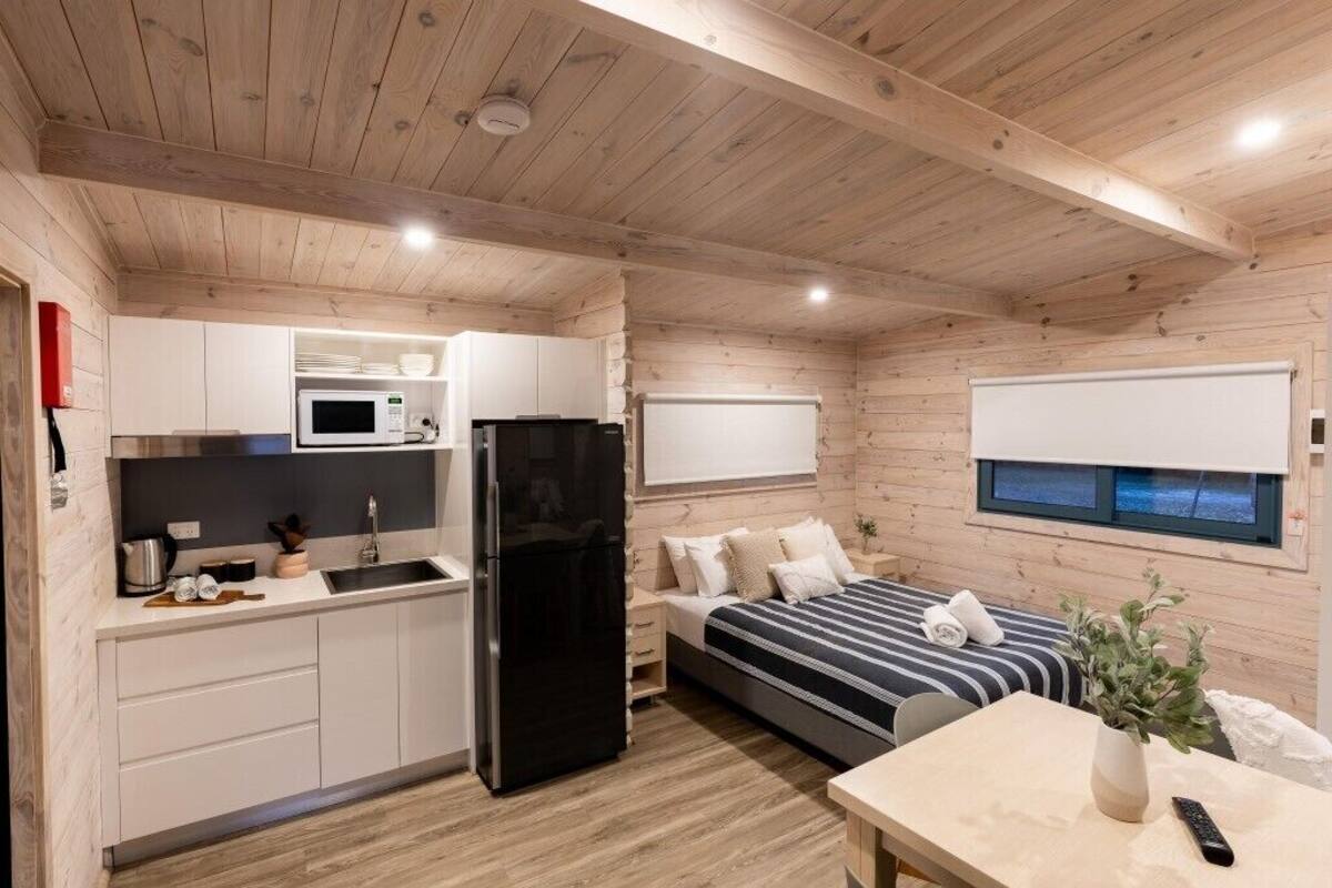 A compact room with a kitchenette, a bed, a small table, and a window.